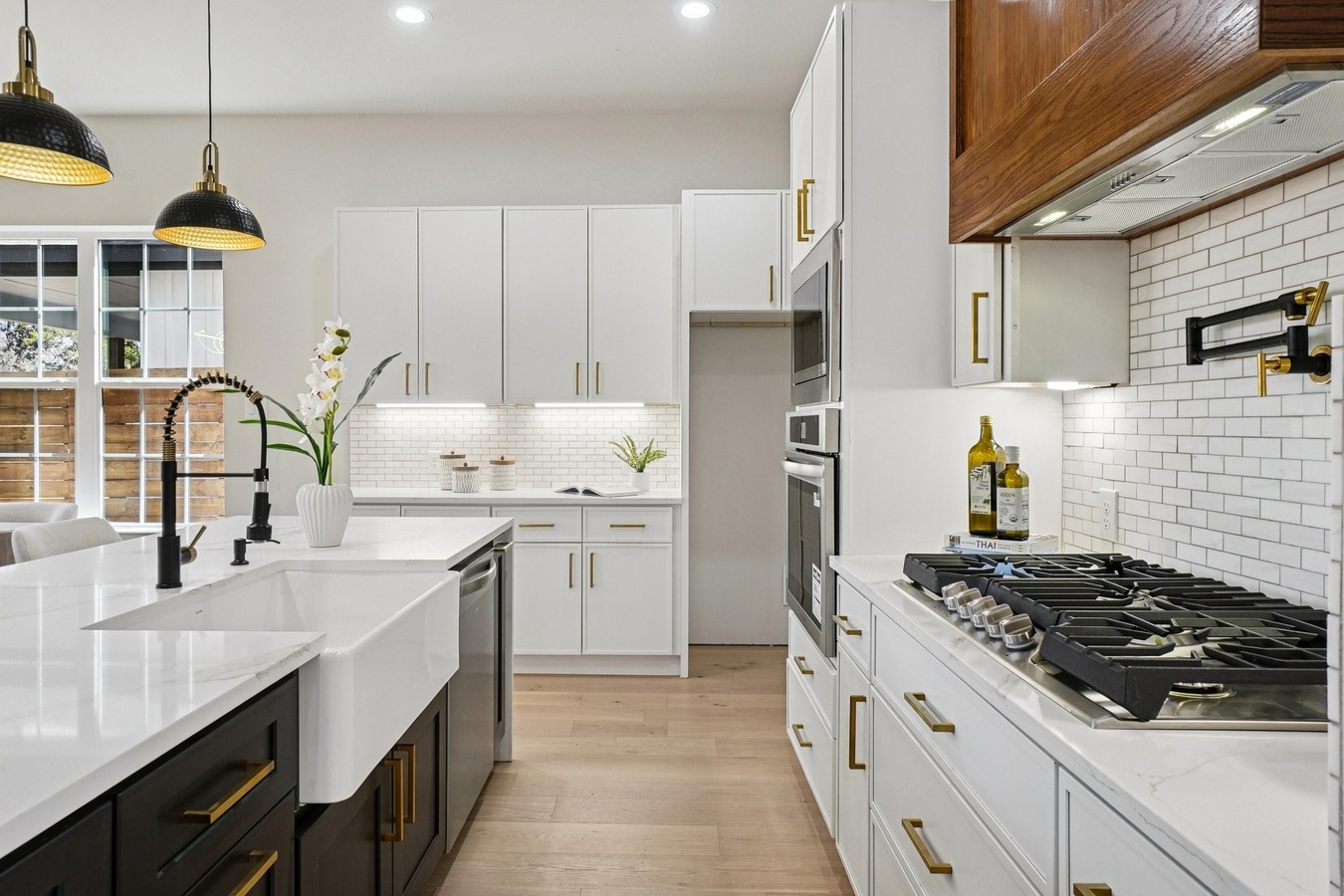 Modern kitchen featuring white shaker cabinets with gold hardware, a white apron-front farmhouse sink, and a classic subway tile backsplash.