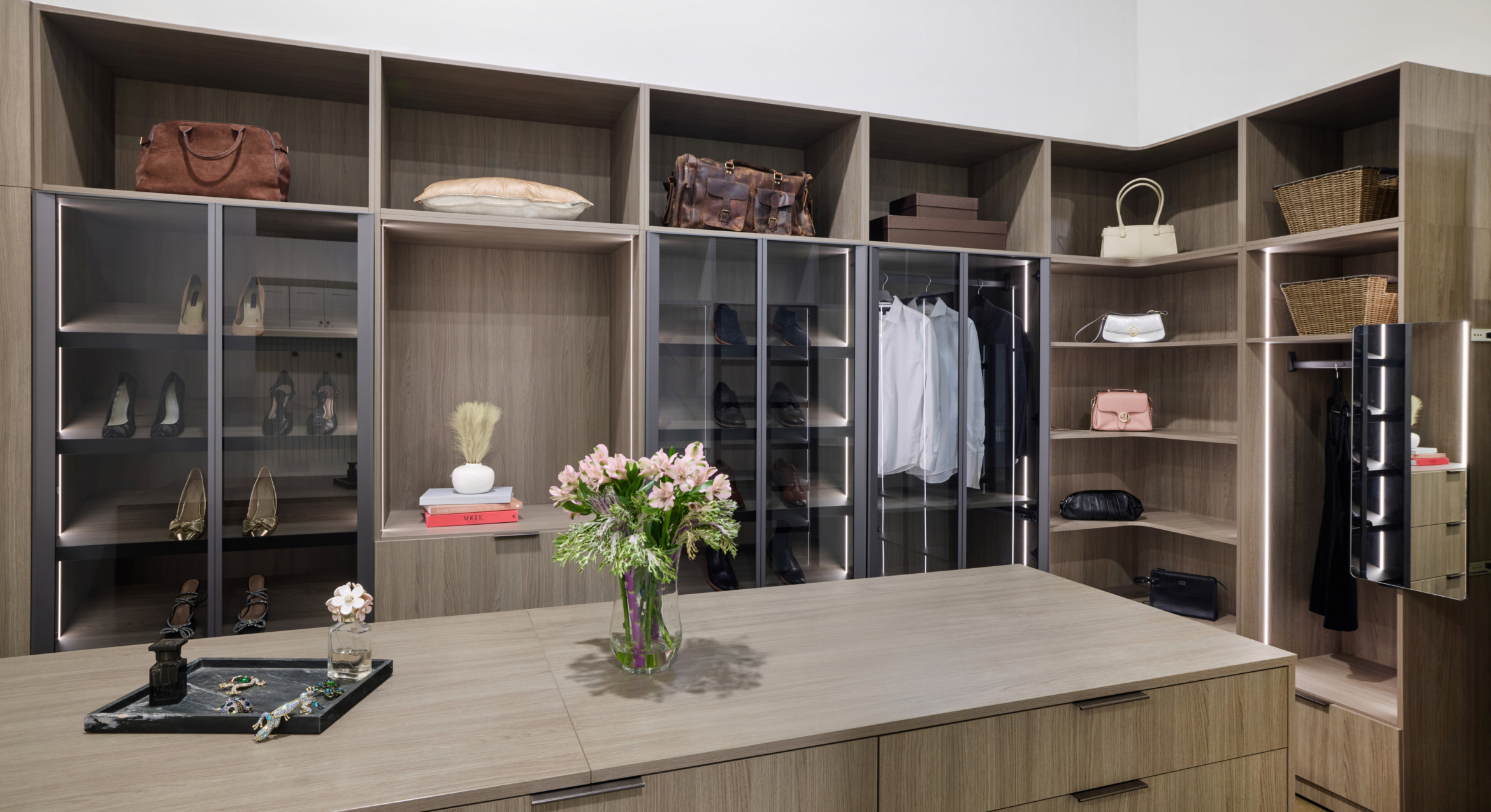 Close-up view of a modern custom dark wood closet system highlighting the hanging rod sections and upper shelf storage.