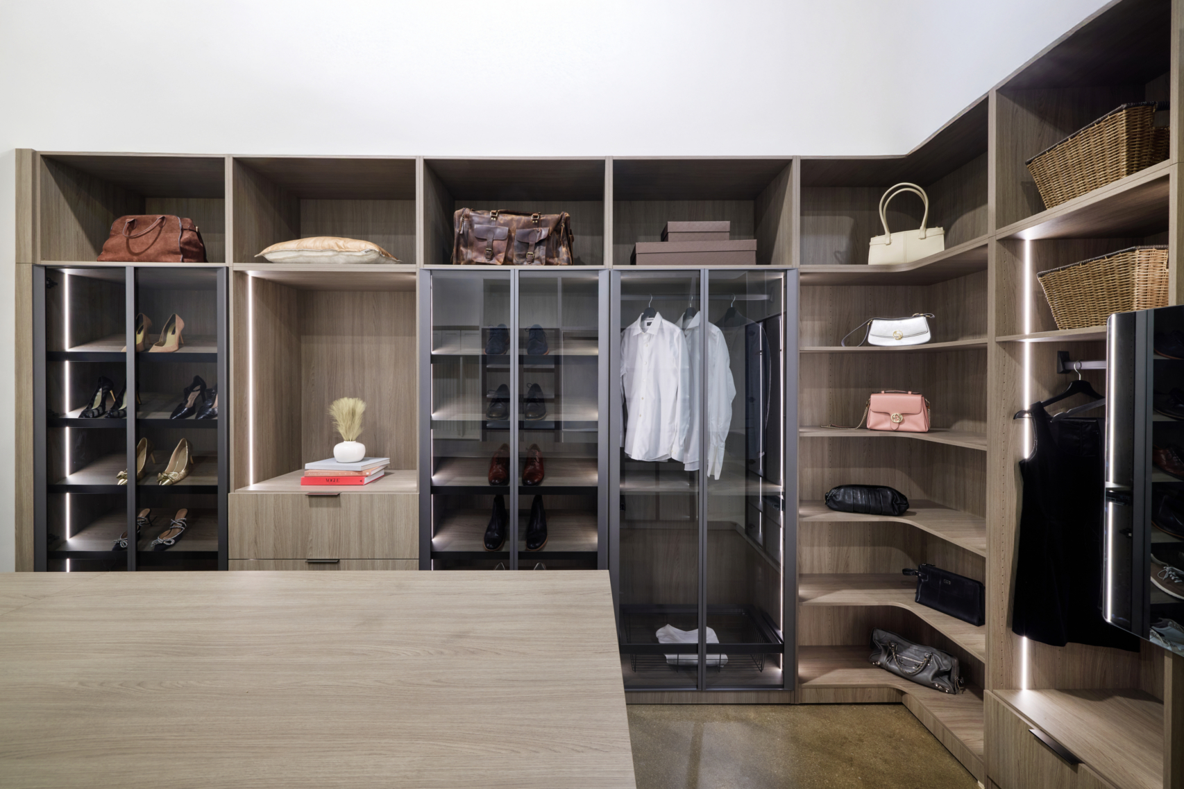 Spacious custom closet featuring dark wood built-in cabinetry, organized hanging sections, and upper storage shelves.