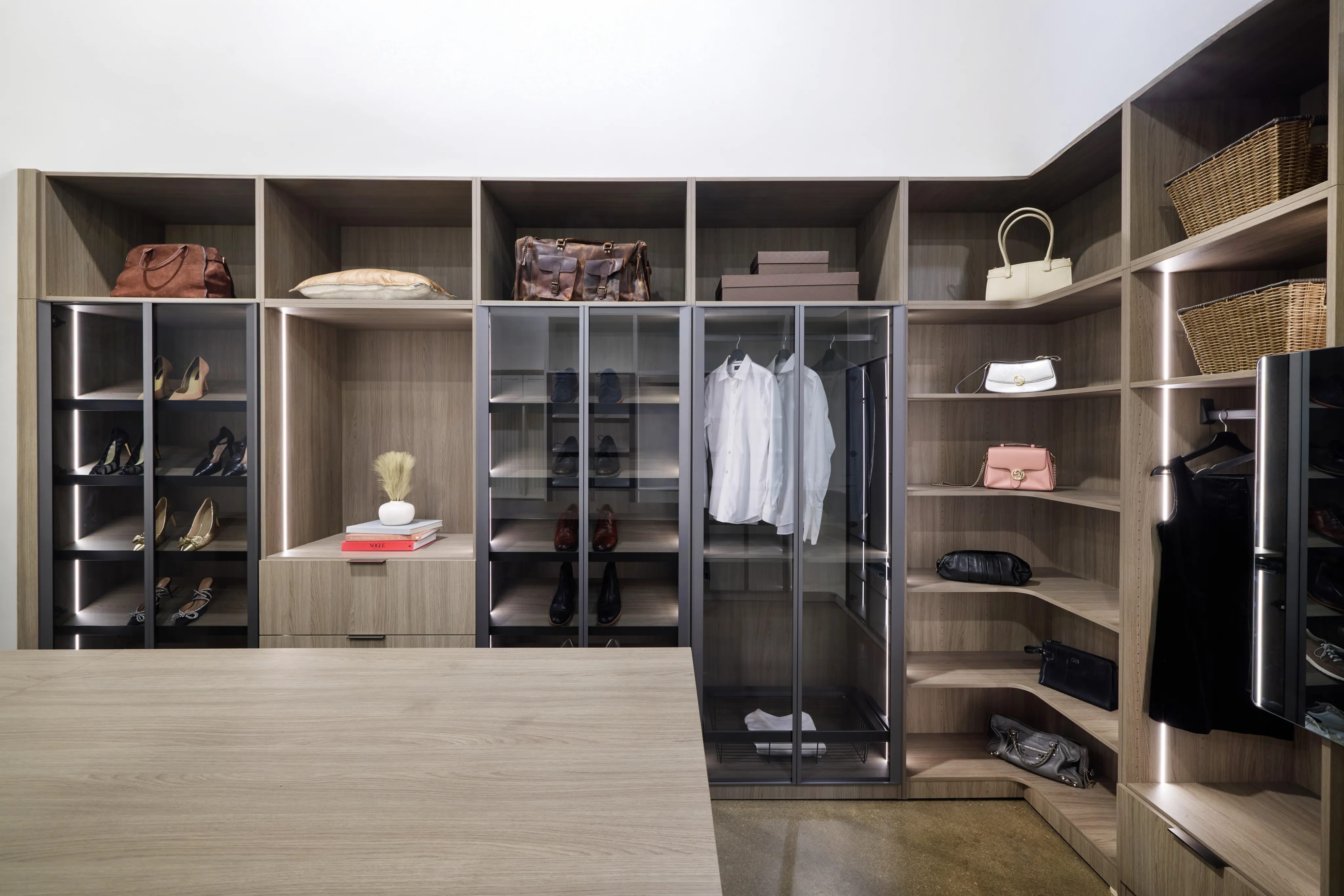 Spacious custom closet featuring dark wood built-in cabinetry, organized hanging sections, and upper storage shelves.