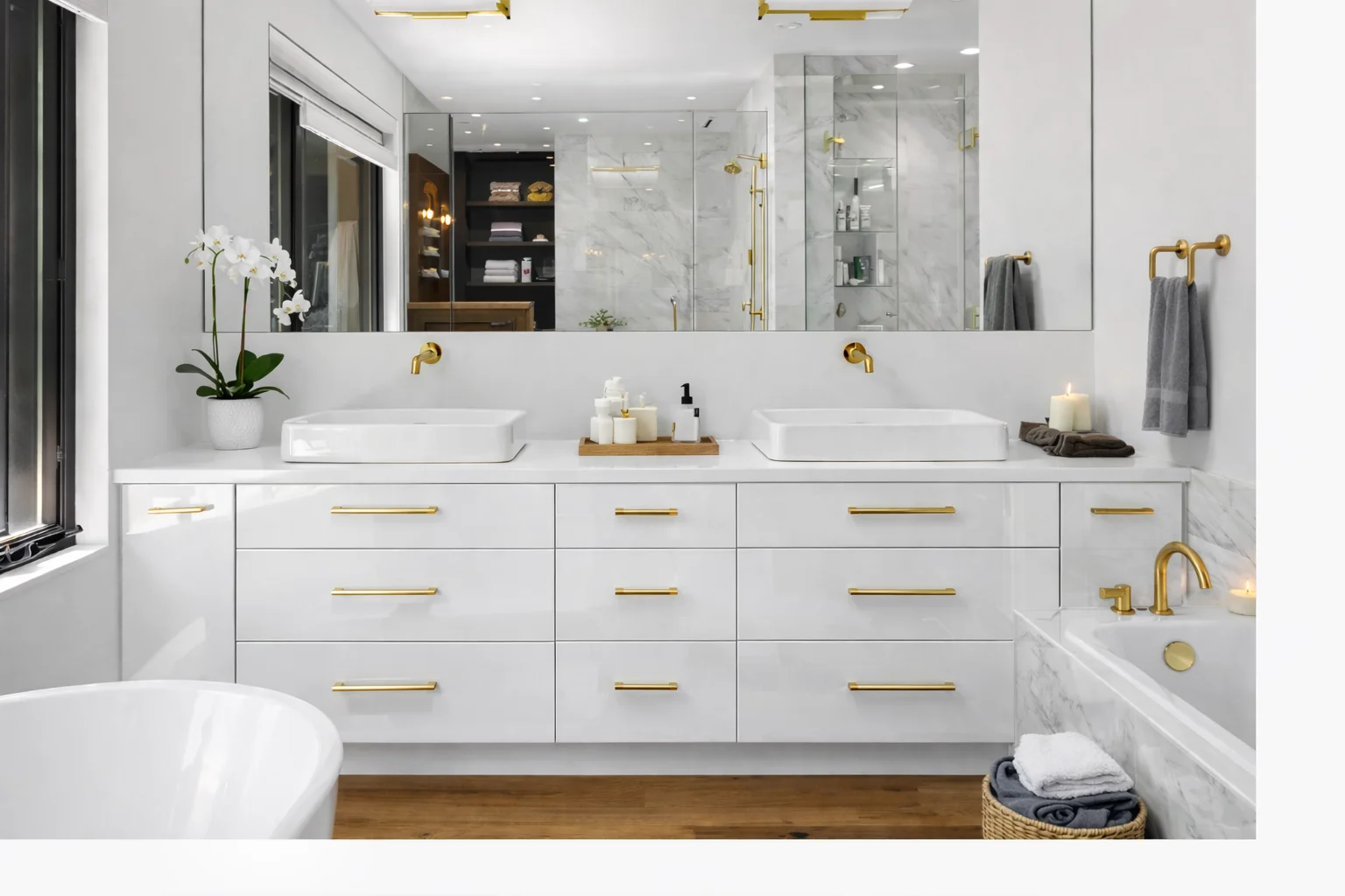 Bright modern bathroom featuring a custom glossy white flat-panel double vanity with gold hardware, dual vessel sinks, a white marble countertop, a large mirror, a glass-enclosed shower, and a white bathtub.