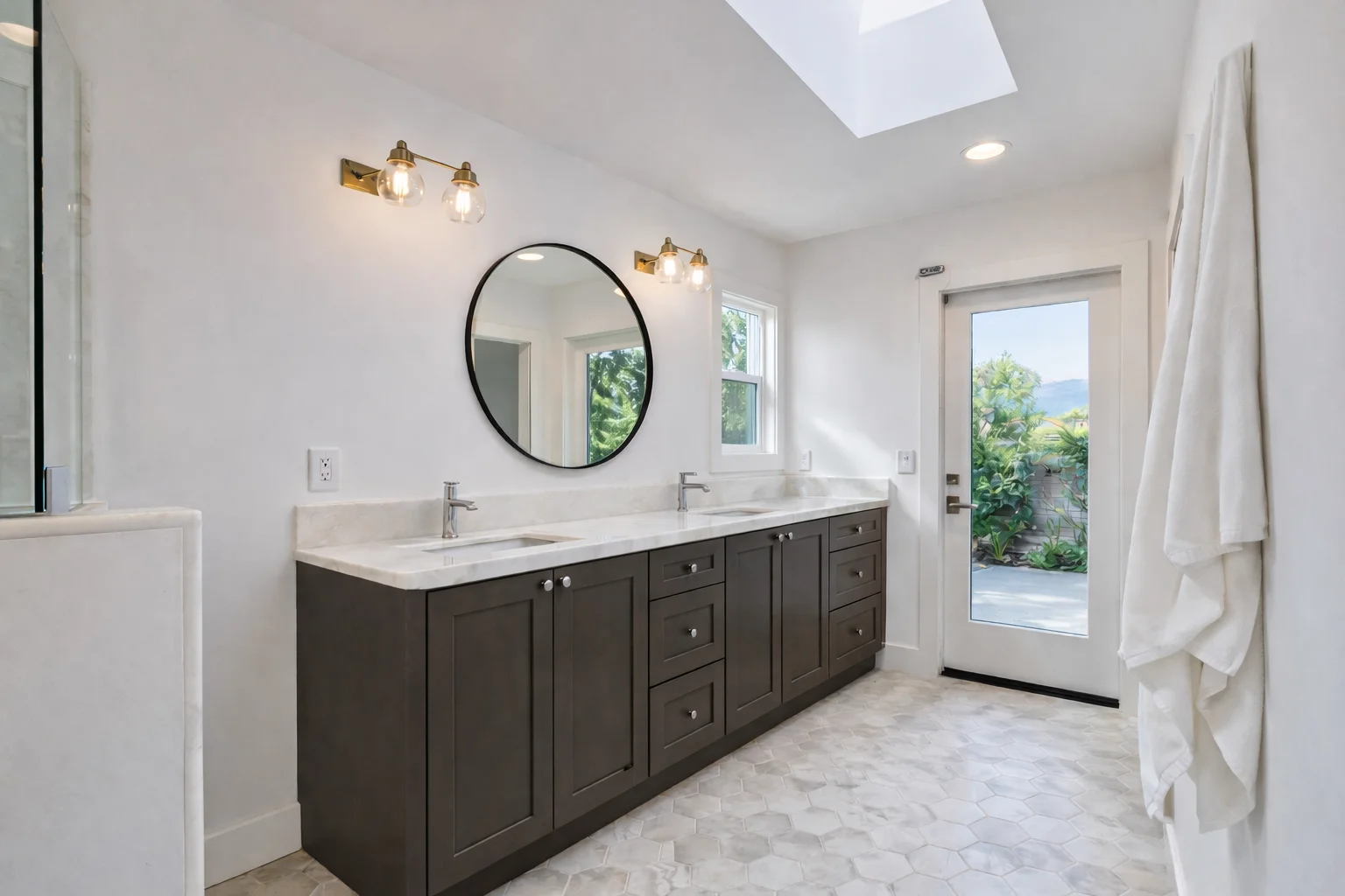 Modern bathroom featuring a custom slate grey single vanity, round mirror, white countertop, and a glass-enclosed shower.