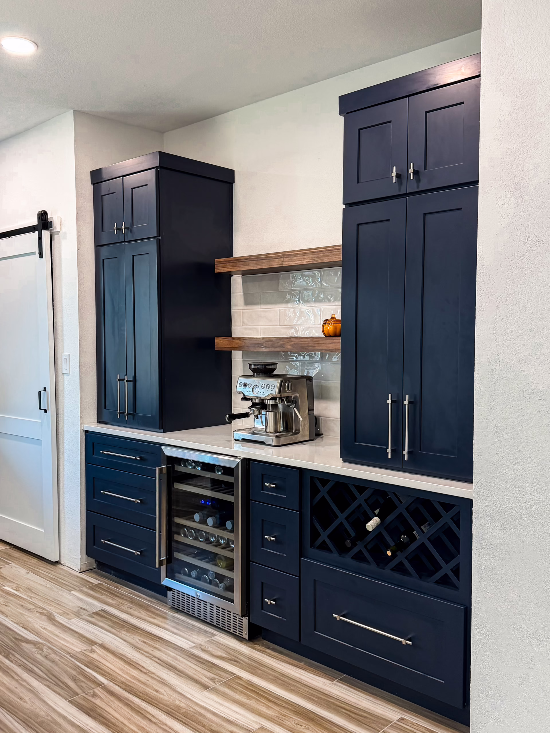 Custom home bar and coffee station featuring onyx black shaker cabinetry, built-in wine rack, beverage cooler, floating wooden shelves, espresso machine, and quartz countertop