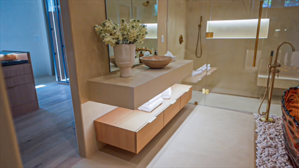 Modern natural oak European frameless floating vanity featuring double drawers and under-cabinet lighting in a luxury primary bathroom with a freestanding tub and walk-in glass shower.