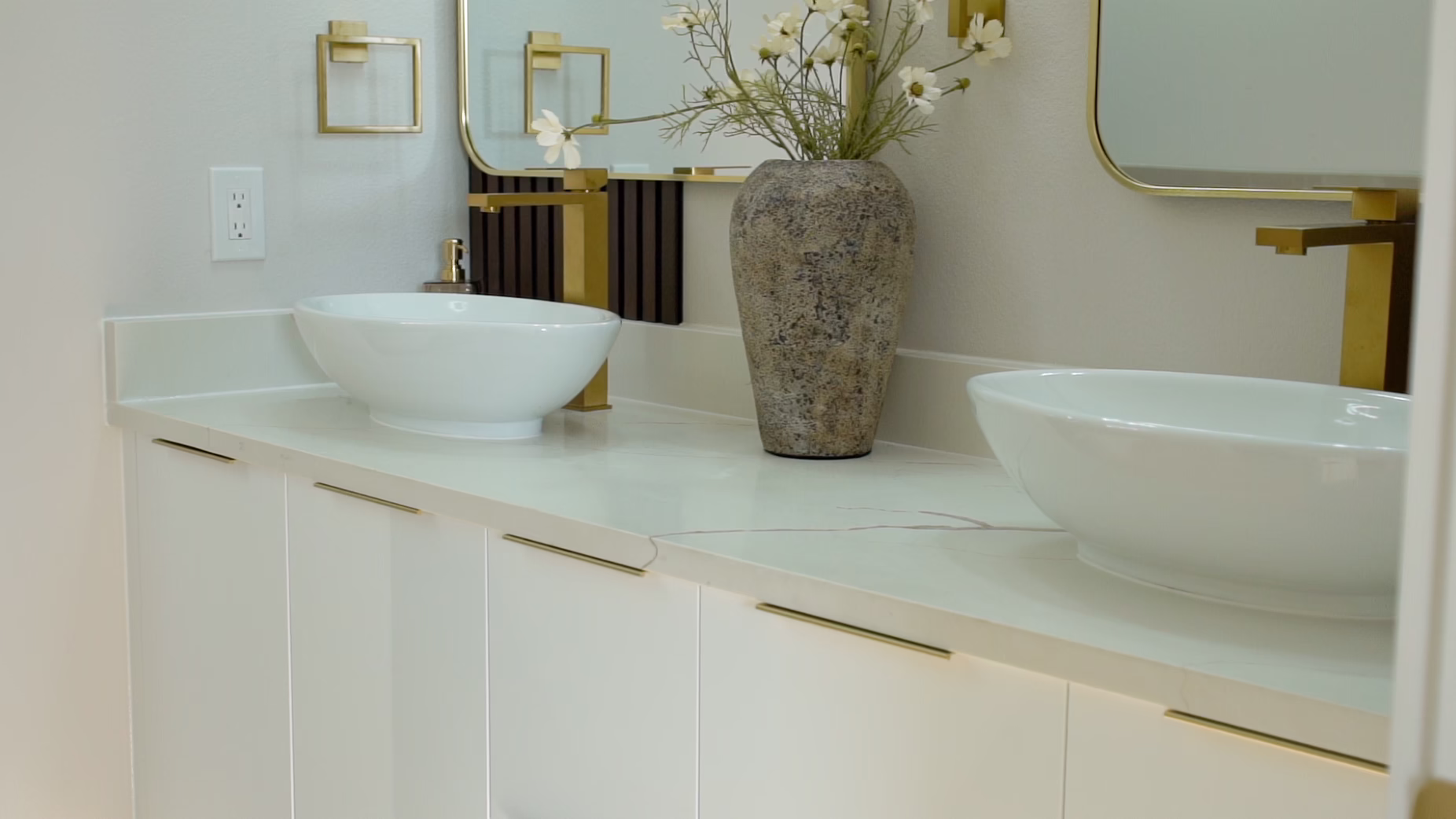 Modern gloss white European frameless floating double vanity with dual white vessel sinks, wall-mounted brass faucets, gold edge pulls, and twin brass-framed mirrors.