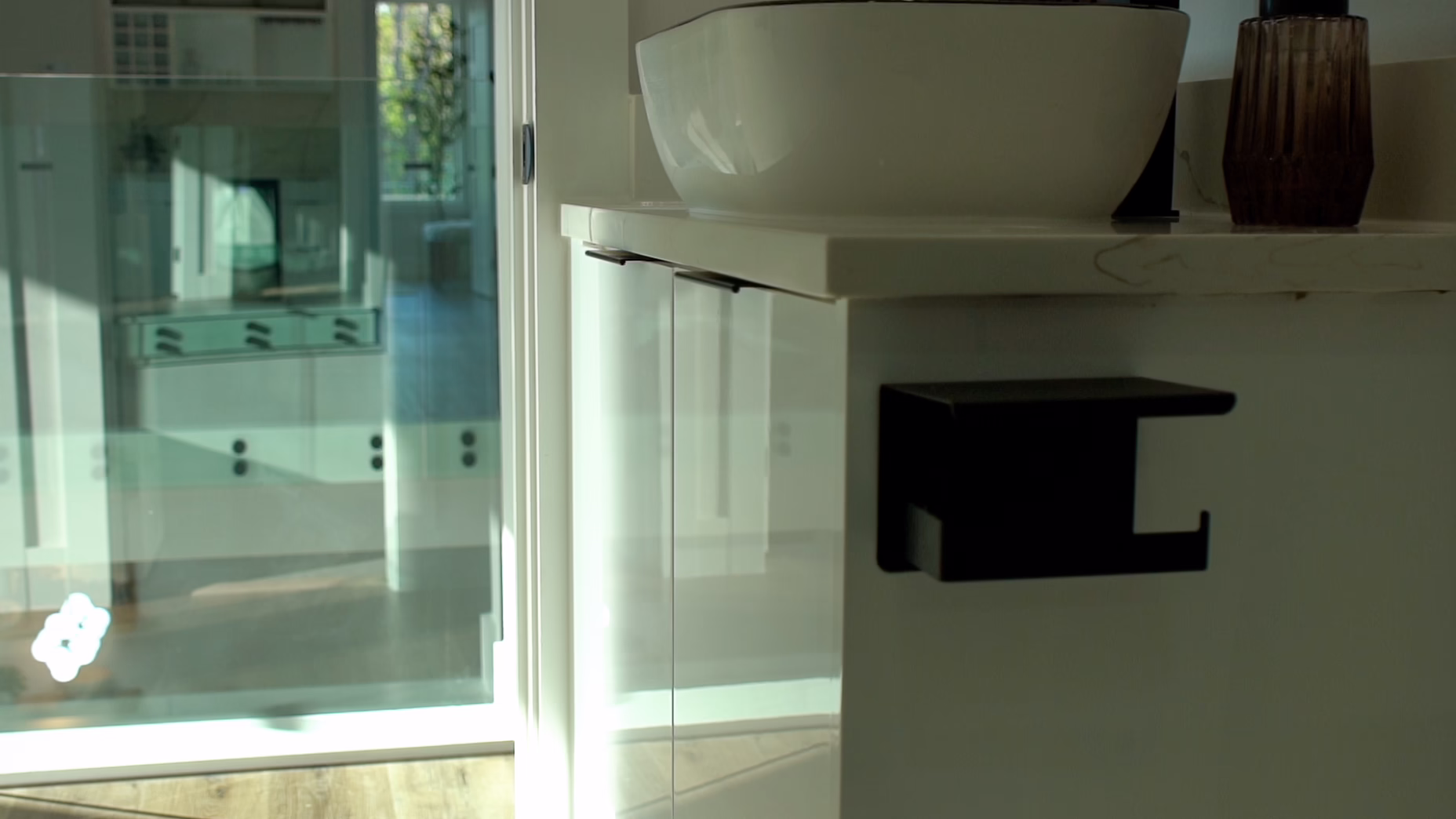 Modern gloss white European frameless floating vanity featuring a white vessel sink and a side-mounted matte black toilet paper holder.